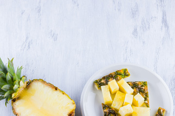 Pineapple slices on a gray background. Sliced pineapple on a white plate. Tropical fruit for vegan. Top view. Copy space