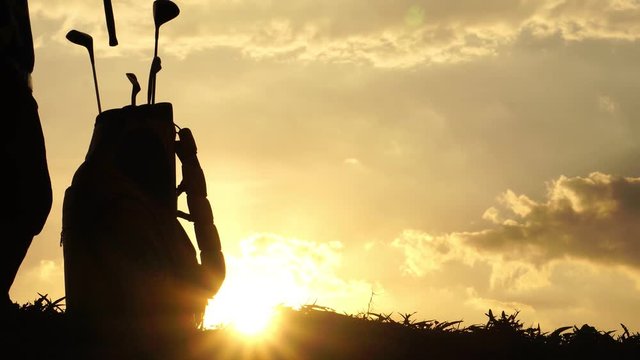 Silhouette male golfers were practicing outside with the sun sets, footage 4K
