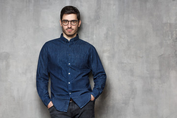 Closeup of serious concentrated European guy standing with crossed arms, isolated on gray background