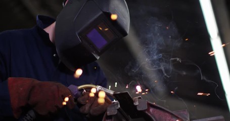 4K Metalworker in in industrial workshop lifting up safety visor & smiling. Slow motion