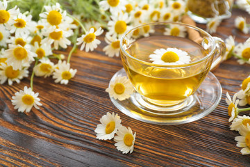 Cup of hot chamomile tea on wooden table