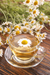 Cup of hot chamomile tea on wooden table