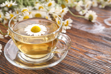 Cup of hot chamomile tea on wooden table