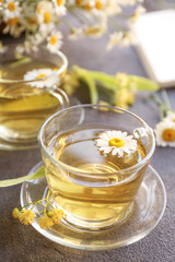 Cup of hot chamomile tea on grey table