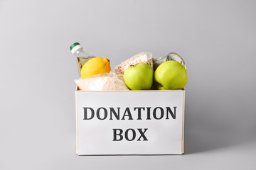 Box with donation food on grey background