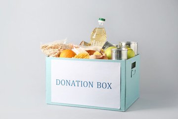 Box with donation food on grey background