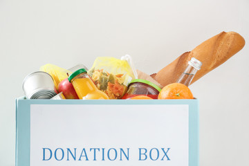 Box with donation food on light background