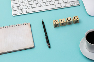 Würfel mit dem Wort „BLOG“ auf dem Schreibtisch, neben einem Kaffee und einem Notizblock