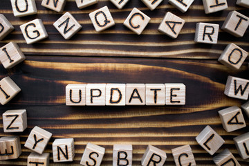 word update composed of wooden cubes with letters, new version information  or changing concept, scattered around the cubes random letters, top view on wooden background