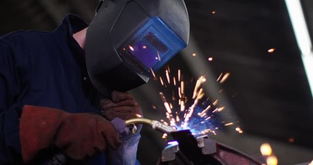 4K Metalworker in industrial workshop using a soldering torch on steel. Slow motion
