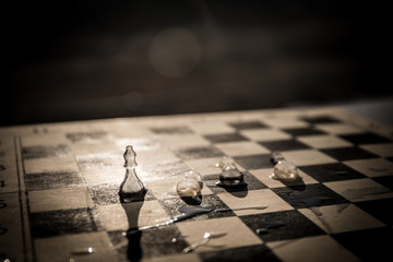 Strategy and tactics concept. Icy frosted chess figures standing on a chessboard during sunset.