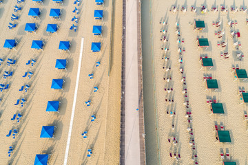 Aerial view of the beach with white sand, umbrellas and chairs.