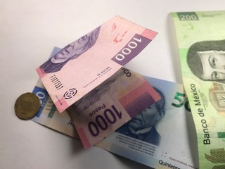Mexican peso bills spread over white background