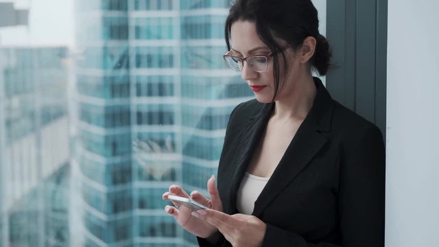 Portrait of a young businesswoman with a mobile phone in her hands. the girl is intently using a smartphone.