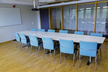 Long white office table with twelve blue chairs in the meeting room.  Business concept. Modern office style. 
