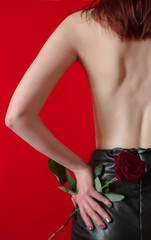 Dangerously beautiful. Attractive young woman with a flower while standing against red background. Woman with rose
