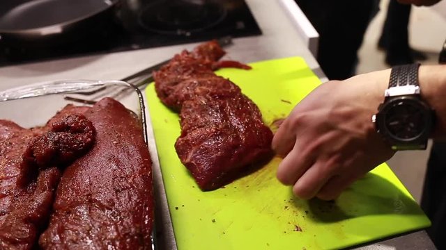 Chef cook cutting meat for steaks on board. Fillet raw meat, food master class, selective focus