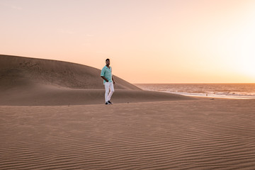 Gran Canaria Maspalomas young men walking at the sand dunes desert during Sunrise at the Canary...