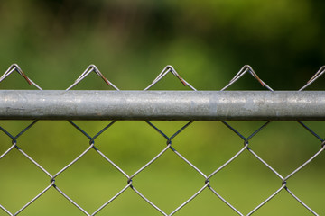 Close up of chain link fence with green background
