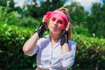 Portrait of an emotional girl in a pink cap visor and protective gloves for rollerblades and skateboarding.