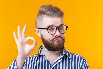 Positive funny hipster shirtless guy with a rocker collar shows ok on a yellow background. Concept of unusual greetings.