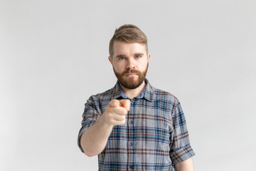 Angry man with beard, finger pointing towards the camera on a white background