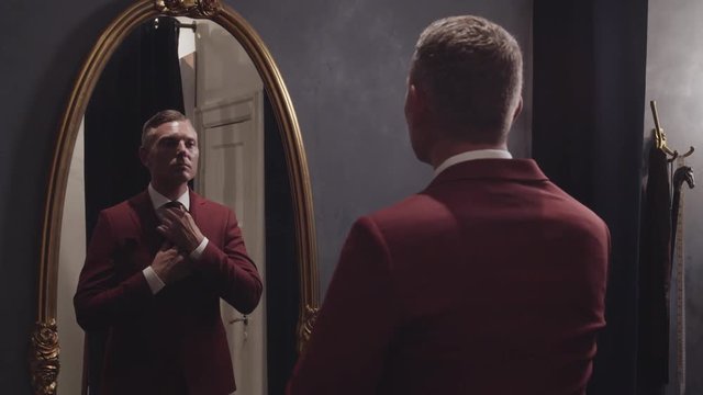 A slow motion clip of a young caucasian male getting dressed in a full length mirror ready for a big date. He is making sure his presentation will make a good first impression.