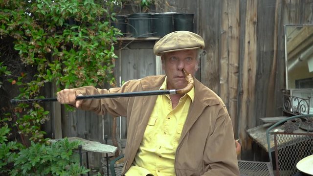 Crazy and funny old guy being silly with his cane, poking his nose. Slow motion.