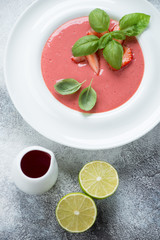 Above view of a white plate with strawberry cream-soup, vertical shot