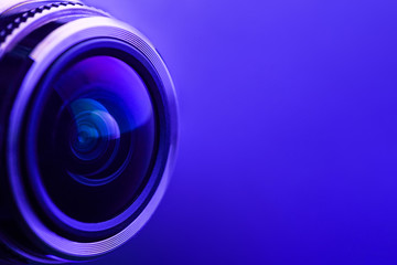 Camera lens with purple backlight. Side view of the lens of camera on purple background. Purple...