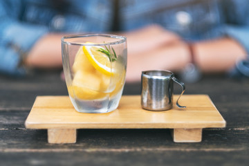 An espresso shot with a glass of ice and lemon