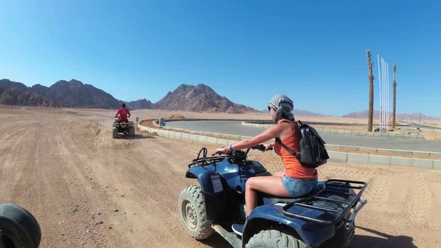 Sexy Woman is Riding a Quad Bike in the Desert of Egypt. Dynamic view in motion.