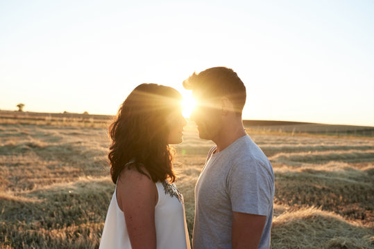 Side view of couple looking at each other on meadow at sunset