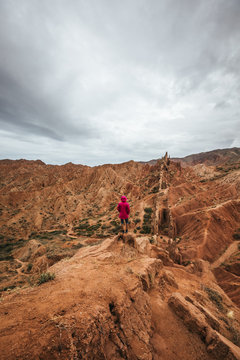 female hiker overlooking valley with bizzare rock formations, kyrgyzstan