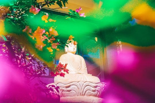 Stone carved statue of Buddha surrounded with colorful flowers