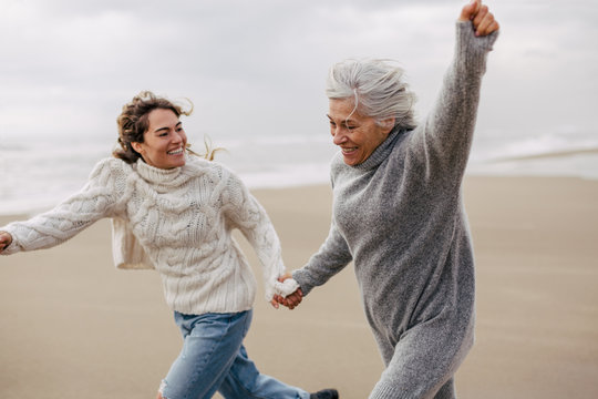 Active senior woman and her daughter enjoying on the beach in winter.