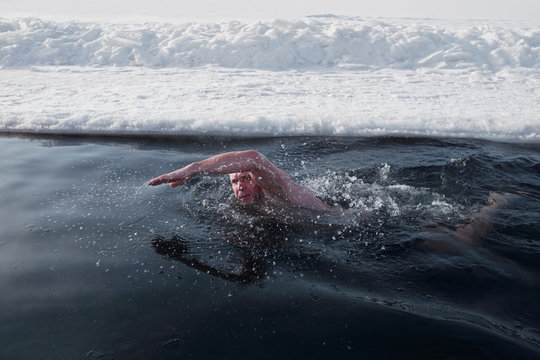 Sportsman swimming in ice hole