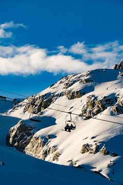 Silhouette of 2 skiers riding a chairlift on a sunny day