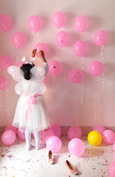 Little girl on her birthday dressed with butterfly wings decorating with ballons and ribbons
