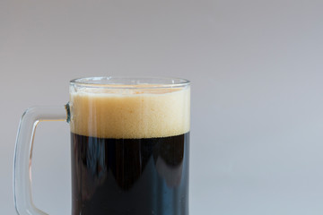 Glass of dark beer on a gray background. copy space