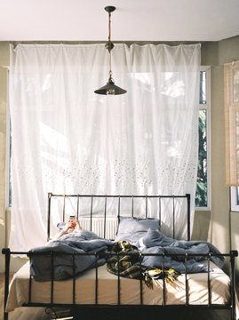 Young man checking his smartphone while in bed