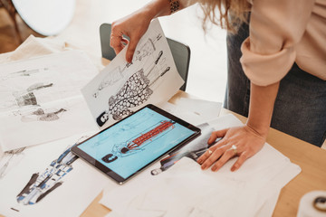 Young female fashion designer uses her tablet to make fashion sketches
