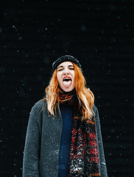 potyrait of a woman in a snowy park catching snowflakes with the tongue