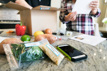 Meal: Couple Removing Ingredients From Box And Looking At Recipe