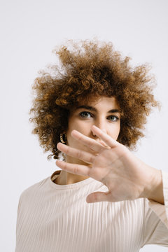 Young curly girl covering face with hand