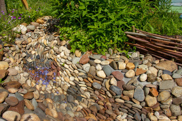 Dry creek in the garden of stones. grass and flowers grow along the bank of the brook.