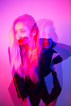 Double exposure photo of a beautiful blonde woman lit with blue and pink colours looking in two different directions.