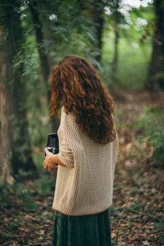 woman with retro camera making pictures in the woods