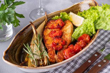 Baked salmon fillet with tomatoes and stern celery on a plate. Diet food. Closeup