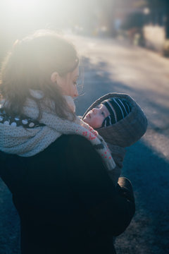 Baby boy in his mother's arms going for a walk in a park in winter
